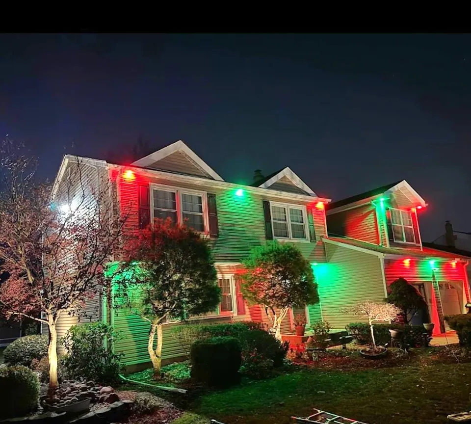 Colonial with red and green permanent roofline lights at Christmas