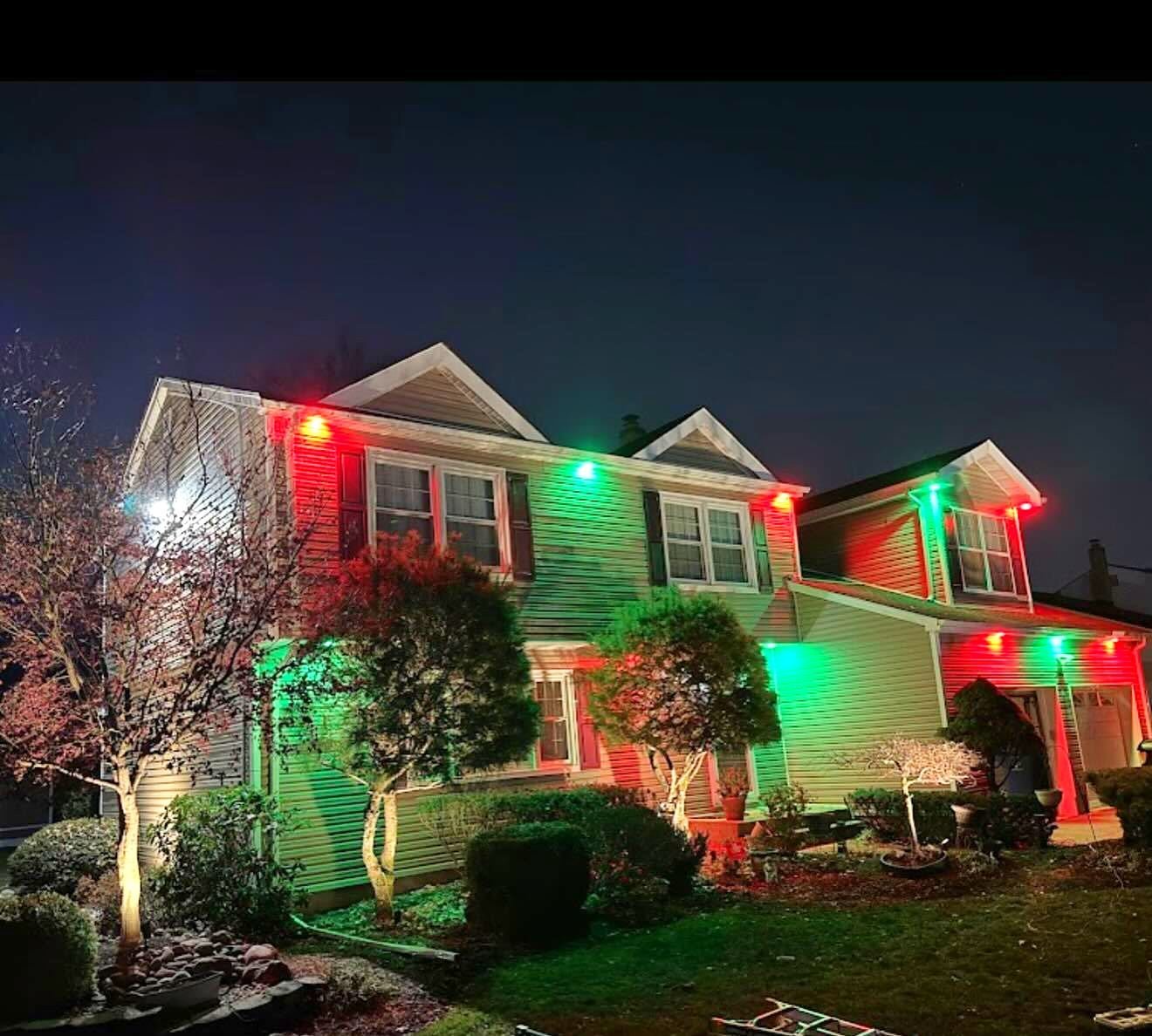 Colonial with red and green permanent roofline lights at Christmas