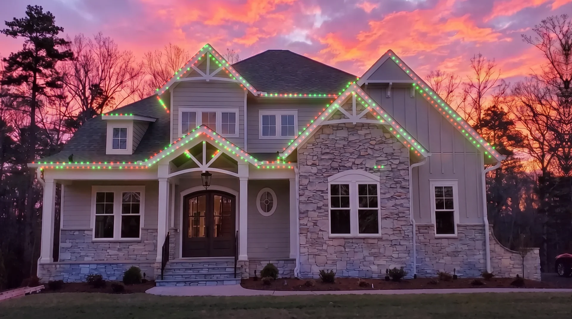 Two story home at sunset with the permanent roofline lighting set to red and green