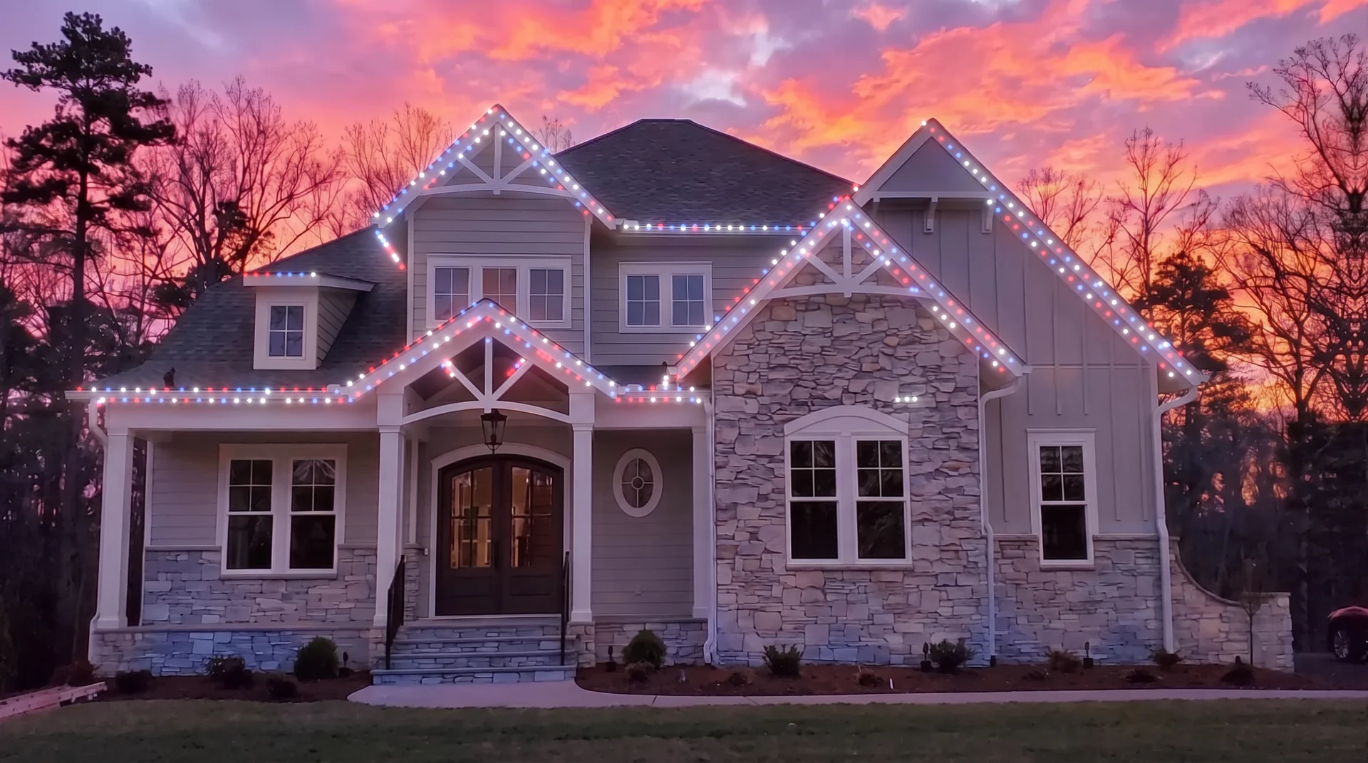Two story home at sunset with the roofline lighting set to red, white and blue