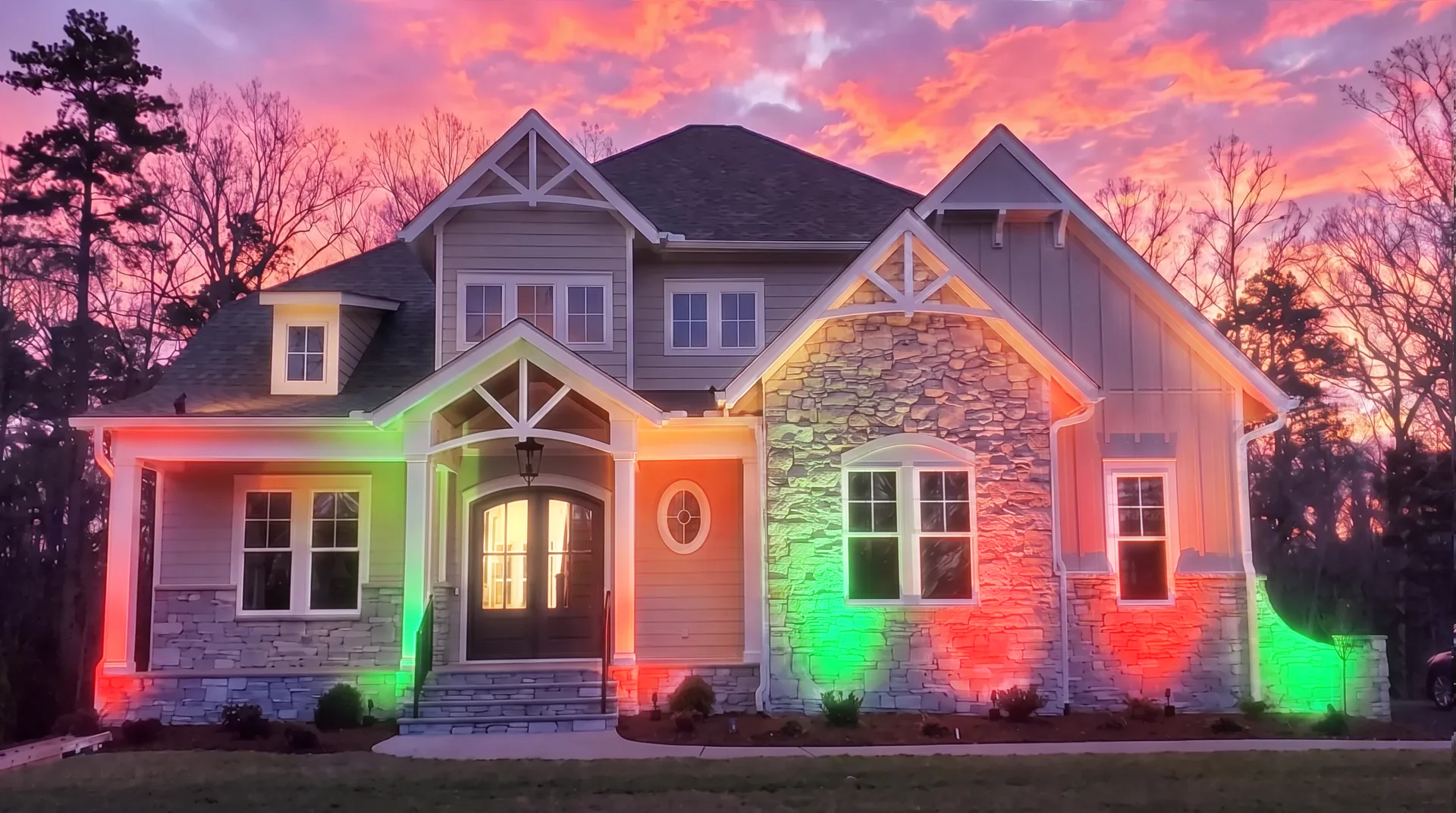 Two story home at sunset with landscape lighting set to red and green